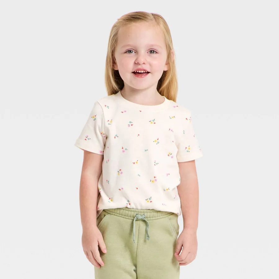Smiling toddler in a floral Cat & Jack tee and soft green joggers on a light gray background